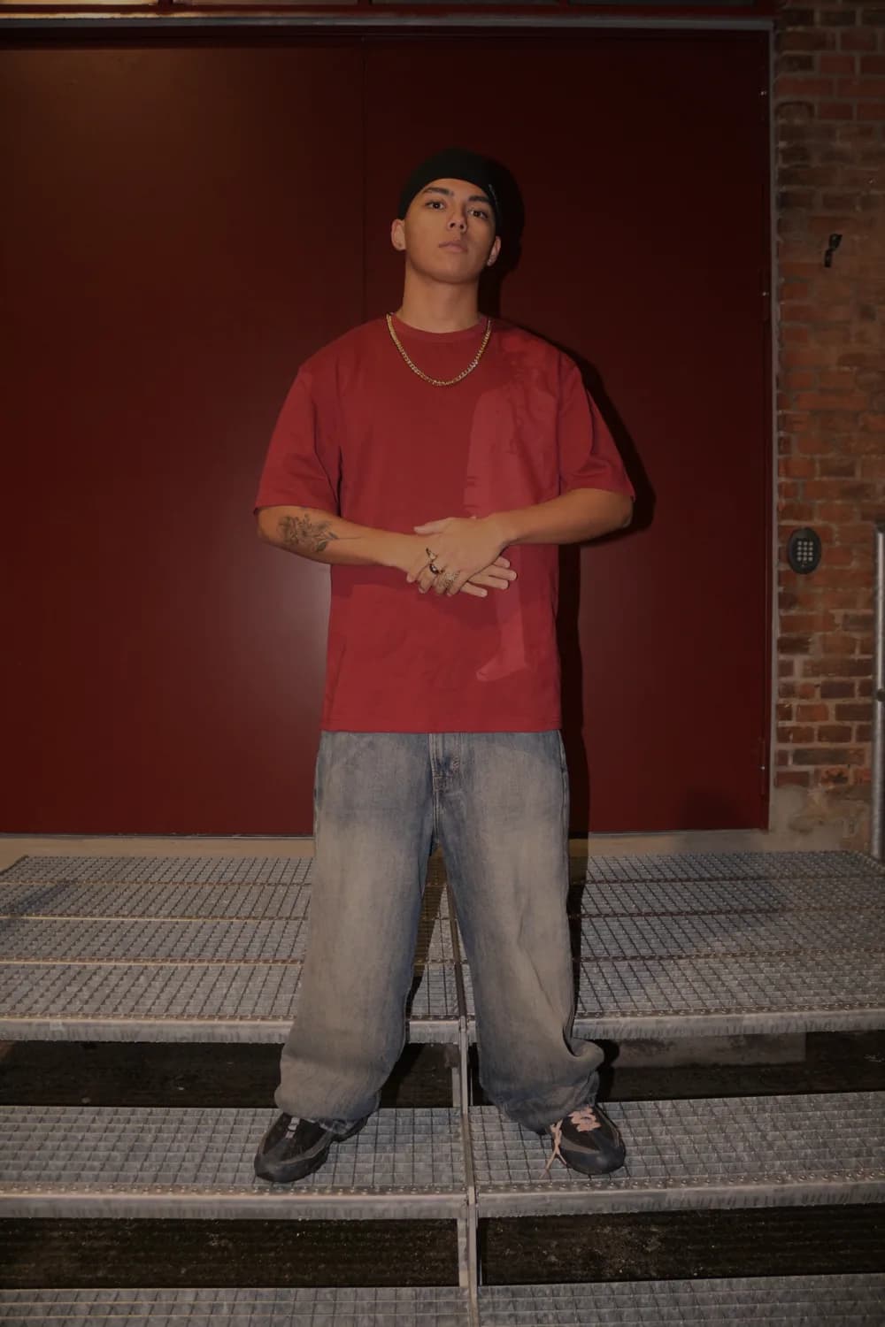 Guy in the bordeaux t-shirt and baggy jeans in front of a red door