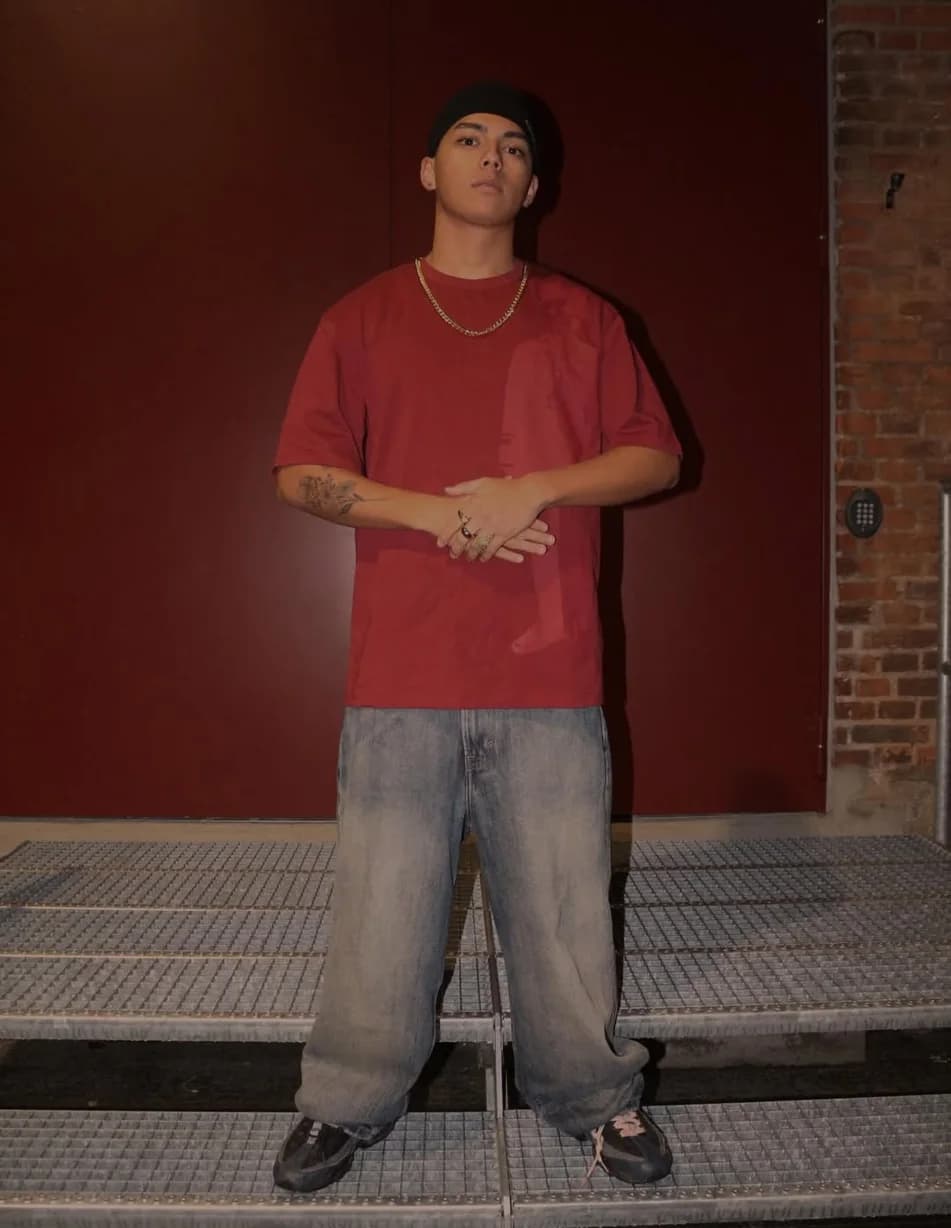 Guy in the bordeaux t-shirt and baggy jeans in front of a red door