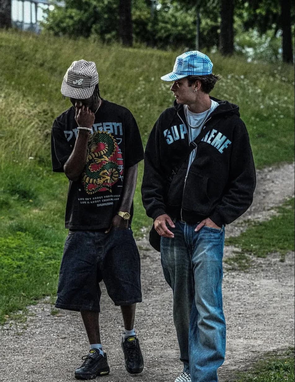 Two guys walking in a park wearing the Tobacco and Glacier caps