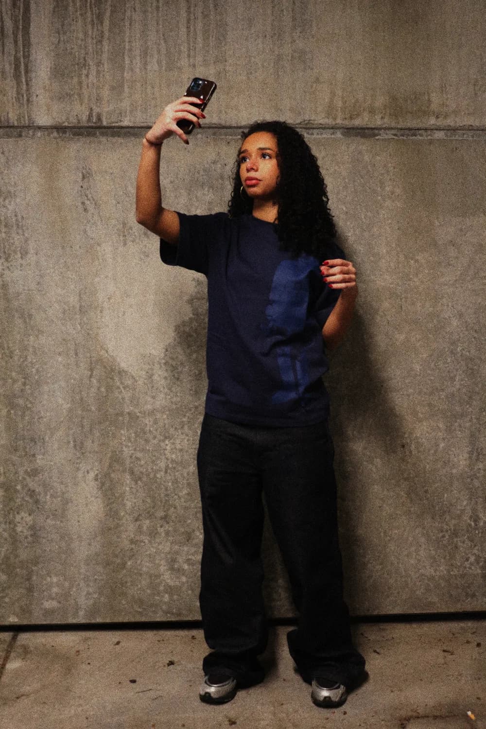 Girl in the navy t-shirt against a concrete wall