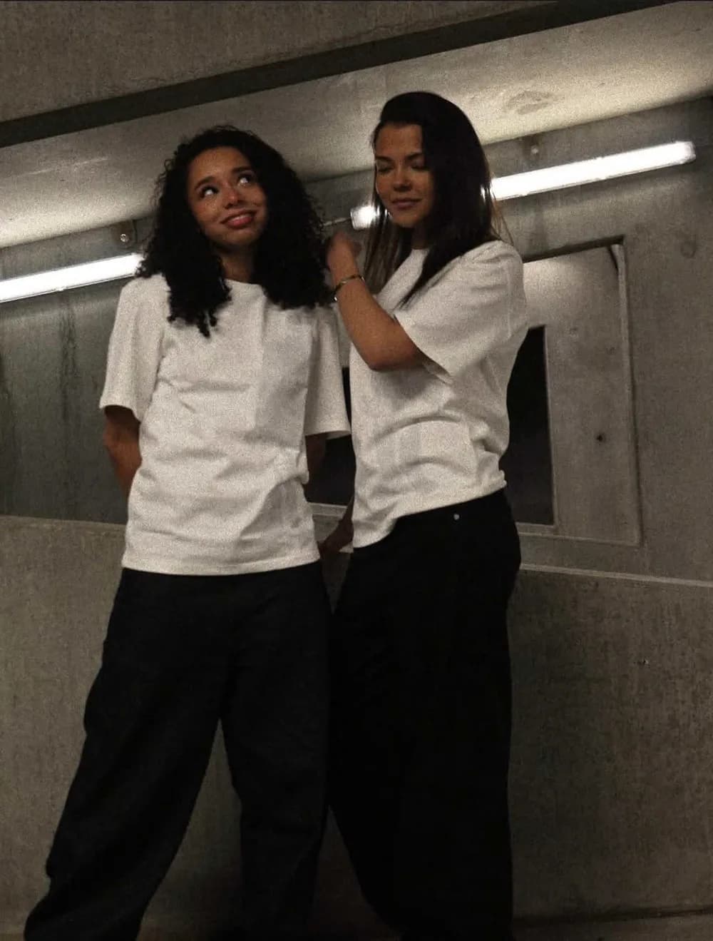 Two girls in white t-shirts in a concrete underpass
